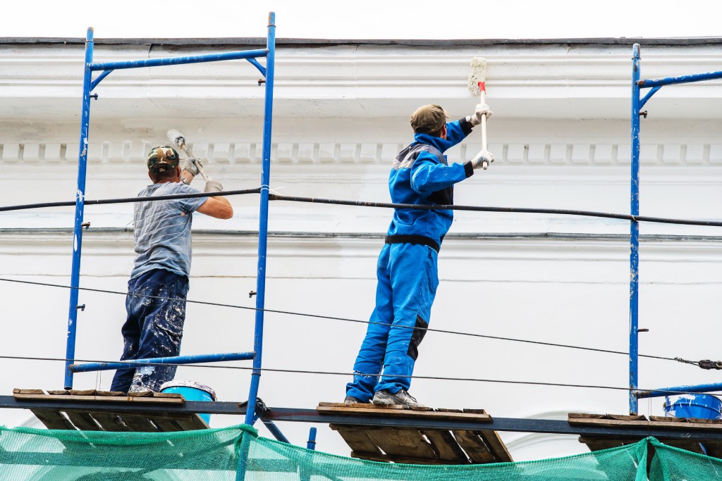 A team of painters painting high walls