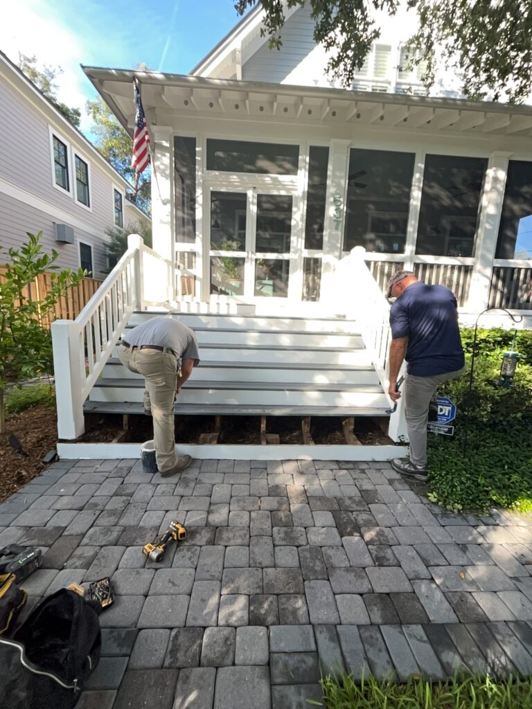 Exterior porch steps and railings being repaired and repainted by a professional painting and carpentry crew.