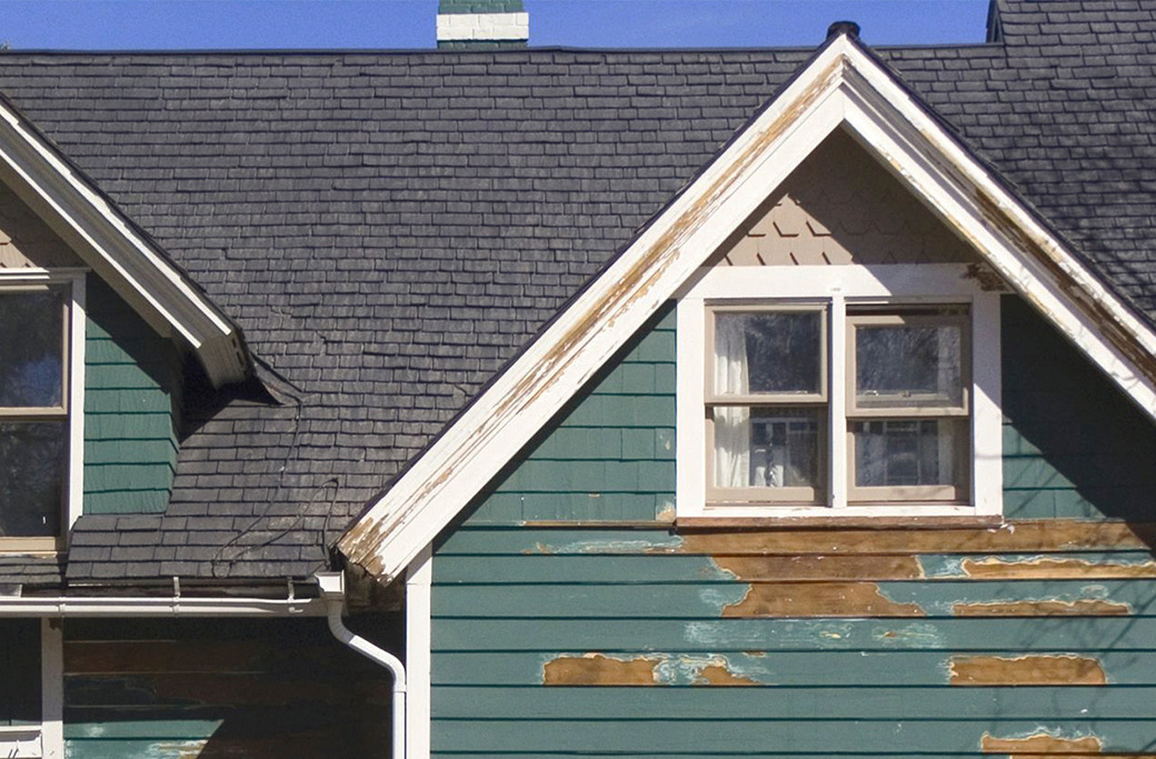 Peeling exterior paint showing loss of adhesion on a coastal home