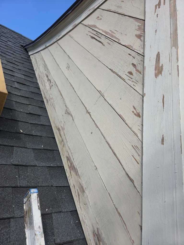 Peeling paint and damaged exterior wood siding along a home roofline before repair