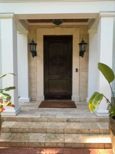 Dark painted front entry door framed by stone and white exterior columns