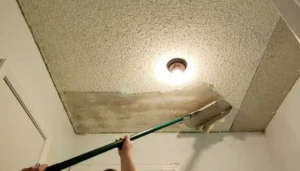 Popcorn ceiling texture being scraped from a residential ceiling during removal