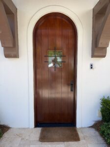 Tall dark wood double front doors with arched transom and stone surround