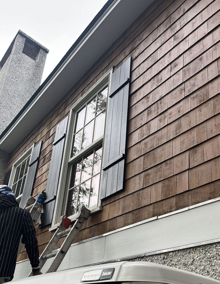 D&D painter working on board-and-batten shutters on a St. Simons Island home