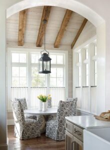 Whitewashed wood plank ceiling with exposed natural wood beams above a bright breakfast nook