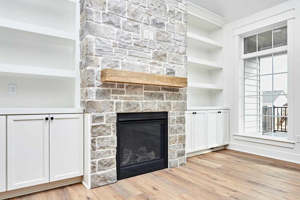 Lightened stone fireplace with natural wood mantel and white built-in cabinets