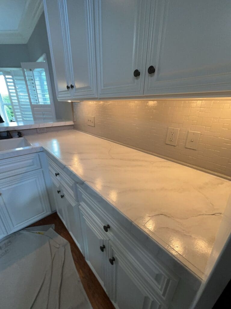 Hampton Point House Painters White kitchen cabinets above a light faux-finish countertop