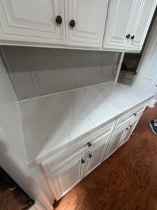 White kitchen countertops refinished with a marble-look faux paint finish and soft gray veining.