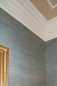 Blue-gray linen-style faux wall finish beneath detailed white crown molding.