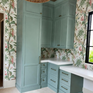 Tropical botanical wallpaper with seafoam green built-in cabinets, white countertops and brass hardware.