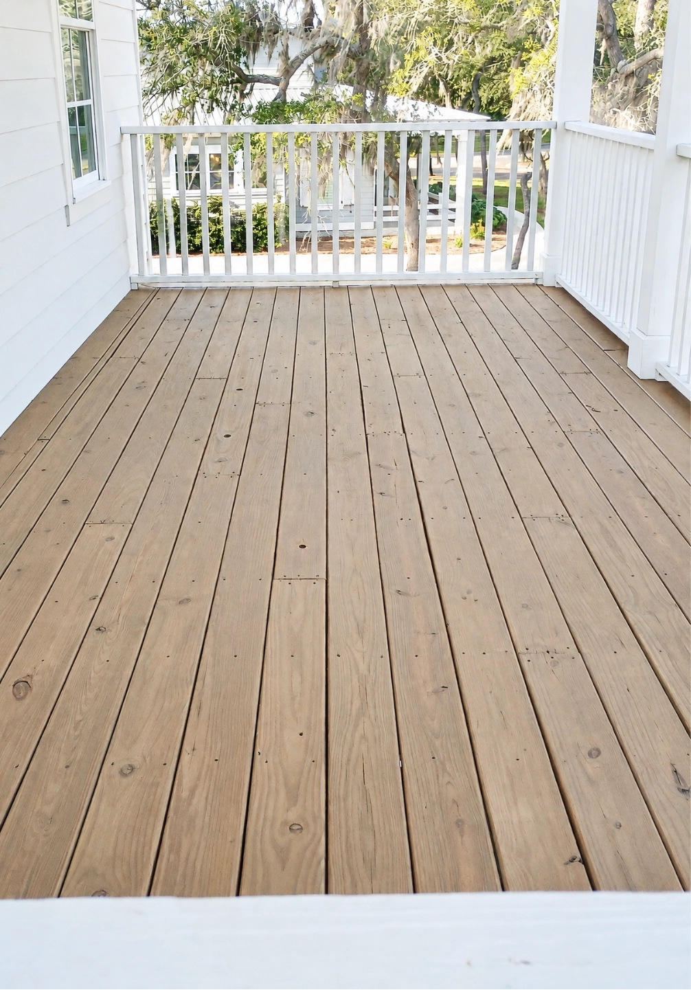 Second-floor front porch deck on St. Simons Island stained in Banyan Brown, with white porch railings