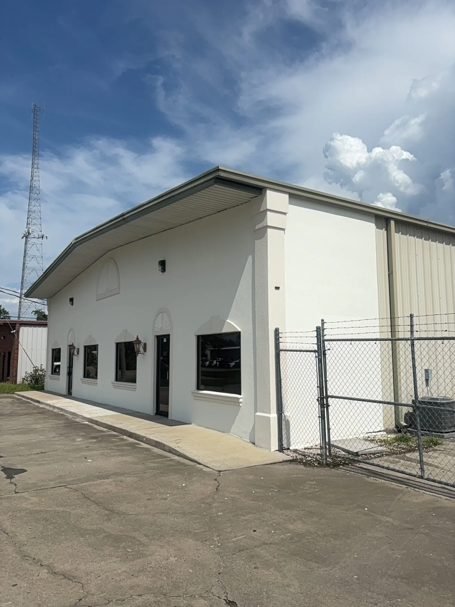 Finished commercial building exterior with freshly painted white walls, trim, window surrounds, and architectural details.