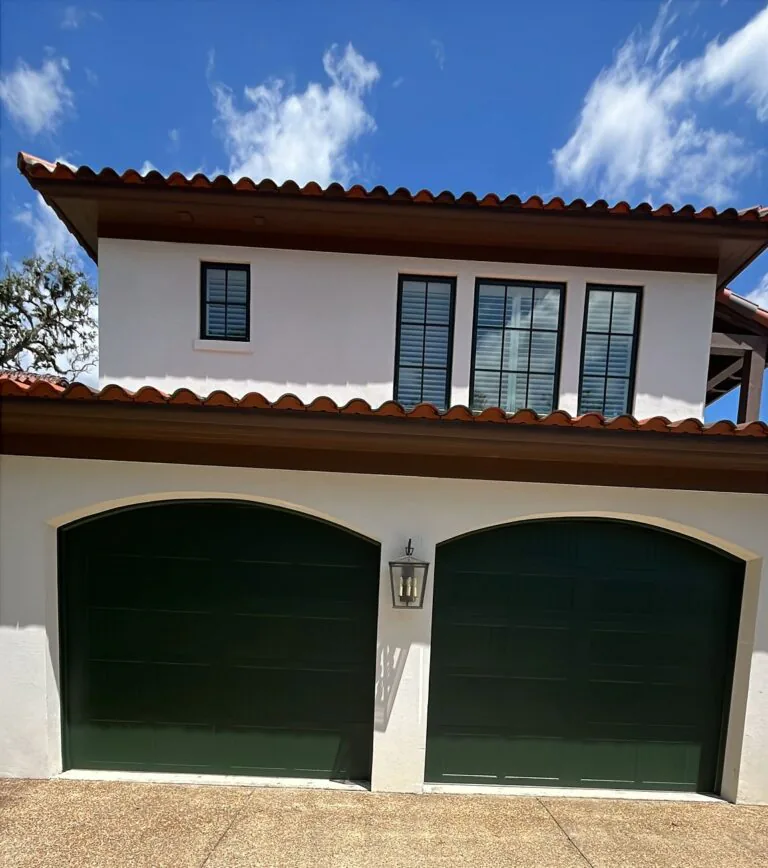 Two dark green painted garage doors on a white stucco St. Simons Island home