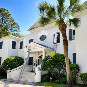 Sea Palms Saint Simons Island White two-story stucco home with black shutters, front steps and a palm tree