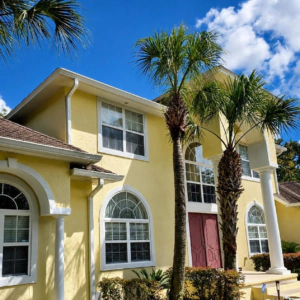 Saint Simons Island Club Yellow two-story stucco home with arched windows and palm trees